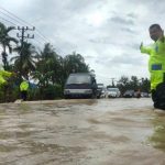 Satlantas Polres Pidie menurunkan personil untuk membantu pengendara melewati jalan yang tergenang banjir.